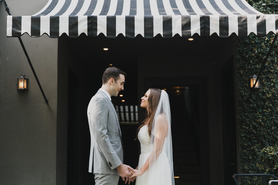bride and groom beneath black and white striped awning